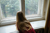 Girl (4-5) looking curiously through window