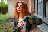 Redhaired woman posing next to old brick house