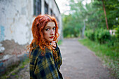 Redhaired woman posing next to old house