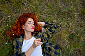 Redhaired woman lying on grass
