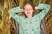 Junge Frau liegt mit geschlossenen Augen auf einem Feld