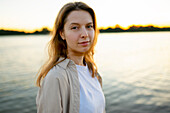 Porträt einer nachdenklichen Frau am Fluss bei Sonnenuntergang