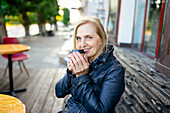 Portrait of smiling woman drinking coffee in sidewalk cafe