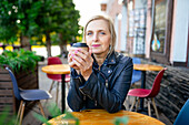 Porträt einer ernsten Frau beim Kaffeetrinken in einem Straßencafé
