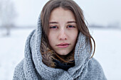 Porträt einer ernsten Frau mit Schal in einer Winterlandschaft