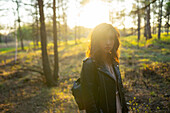 Porträt einer Frau, die an einem sonnigen Tag im Wald steht