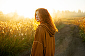 Porträt einer ernsten Frau, die bei Sonnenaufgang auf einem Feld steht