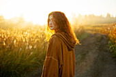 Portrait of serious woman standing in field at sunrise