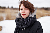 Porträt einer ernsten Frau, die in die Kamera schaut, während sie in einem Winterfeld steht