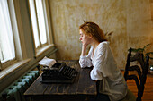 Seitenansicht einer Frau, die zu Hause eine alte Schreibmaschine benutzt