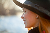 Porträt einer lächelnden Frau mit Hut bei Sonnenuntergang