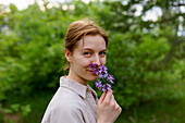 Portrait of smiling woman smelling lilac flower