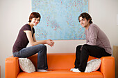 Young couple sitting on sofa and looking at camera