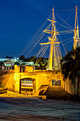Die Puerta de Don Diego oder Don Diego Tor in der Stadtmauer der alten Kolonialstadt Santo Domingo, Dominikanische Republik. UNESCO-Weltkulturerbe der Kolonialstadt Santo Domingo. Dahinter liegt ein Segelschiff im Hafenbecken.