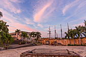 Alcazar de Colon oder Kolumbus-Palast auf der spanischen Plaza, Kolonialstadt Santo Domingo, Dominikanische Republik. Erbaut von Gouverneur Diego Kolumbus zwischen 1510 und 1514. Puerta de Don Diego oder Don Diego Tor in der Mitte. UNESCO-Welterbestätte der Kolonialstadt Santo Domingo. Im Hintergrund liegt ein Segelschiff am Kai.