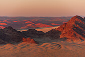 Light illuminates the Naukluft Mountains and Namib Desert at sunrise. Namib Naukluft Park, Namibia.