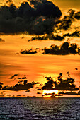 The crimson light of the setting sun reflects a red glow on the beach at Pererenan Beach, Bali, Indonesia