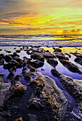 Das goldene Licht der untergehenden Sonne reflektiert einen goldenen Schimmer auf dem Strand von Pererenan Beach, während die Wellen auf Bali, Indonesien, anrollen