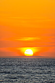 The golden light of the setting sun reflects a gold glow on the beach at Pererenan Beach, as the waves roll in on Bali, Indonesia