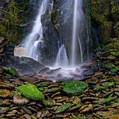 Irland, Ferriter's Cove. Nahaufnahme eines Wasserfalls und moosbewachsener Felsen.