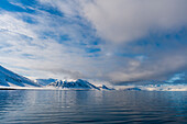 Snow covered mountains rise near the shore of Mushamna Bay. Spitsbergen Island, Svalbard, Norway.