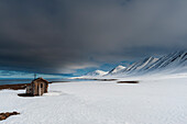 Eine Fuchsjagdhütte am schneebedeckten Strand von Mushamna, Insel Spitzbergen, Svalbard, Norwegen.
