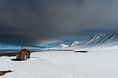 A fox hunting log cabin on the snow covered beach at Mushamna, Spitsbergen Island, Svalbard, Norway.