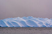 An iceberg in Ilulissat Icefjord, a UNESCO World Heritage Site, on a cloudy day. Ilulissat Icefjord, Ilulissat, Greenland.