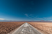 Eine leere Straße durch eine Salzwüste im Salar de Atacama. Salar de Atacama, Atacamawüste, Region Antofagasta, Chile.