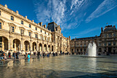 Besucher spazieren in der Nähe des Palais Royal unter einem klaren blauen Himmel.