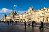 Visitors walking near the Palais Royal under a clear blue sky.