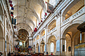 The interior of La Catedral de Saint-Louis-des-Invalides in Paris, France, featuring high vaulted ceilings and flags suspended from the ceiling.