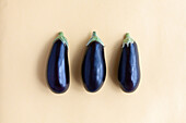 From above of seamless background of fresh ripe aubergines placed on pastel yellow background