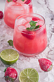 From above of glasses of cold coconut water with strawberries served on ice background