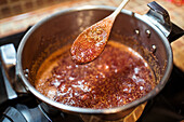 From above of crop anonymous person stirring fig confiture in cooker on stove at home