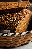 Closeup of tasty cut bread with brown crust and crunchy sunflower seeds on top in wicker basket