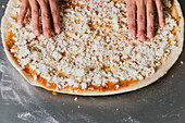 From above cropped unrecognizable female chef in uniform cooking delicious pizza on kitchen counter
