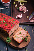 From above delicious homemade meat loaf with carrot served with fresh green parsley on wooden chopping board on table
