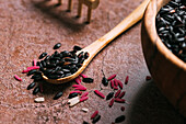 Closeup soft focus of wooden spoon with bunch of fresh black rice placed on table in kitchen