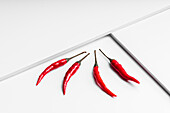 High angle composition of hot red chili peppers arranged plate against white geometric surface background