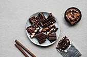 Draufsicht auf verschiedene Schokoladentafeln und Schokoladencreme vor einem Zementhintergrund