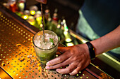 Unbekannter Barkeeper hält Glas und rührt Mojito-Cocktail in der Bar
