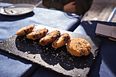 Leckere gebratene Nuggets mit Soße auf einer Schiefertafel auf einem Tisch in einem Straßencafé an einem sonnigen Tag