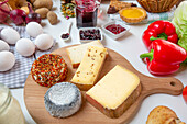 Assorted goat and cow milk cheese placed on wooden chopping board near bread and sauces