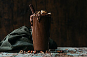 Front view of natural milkshake of chocolate in dark scene with nuts