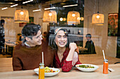 Fröhliches multiethnisches Paar isst gesundes Frühstück im Restaurant