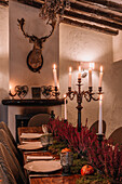 Interieur eines Esszimmers mit Holztisch, Besteck und mit Blumen dekorierten Tellern für das Abendessen