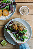 Top view of anonymous person taking yummy sweet potato falafel from cutting board over napkin and timber table in kitchen