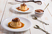 Eipudding mit süßer Dulce de leche, serviert auf weißen Tellern auf einem Tisch mit Besteck in der Küche, von oben