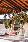 Close-up of transparent glass vases with bunches of fresh flowers placed on table for event